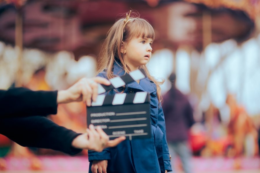 Young female child actor behind a clapboard on a movie set