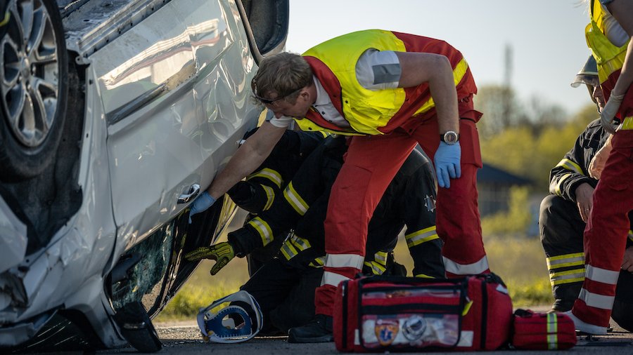 EMT tratando de liberar a un pasajero de un SUV volcado