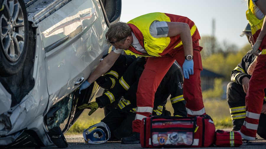 EMT trying to free a passenger from an overturned SUV