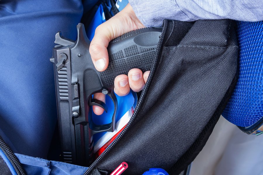 Hand holding gun in backpack at school in violation of NRS 202.265