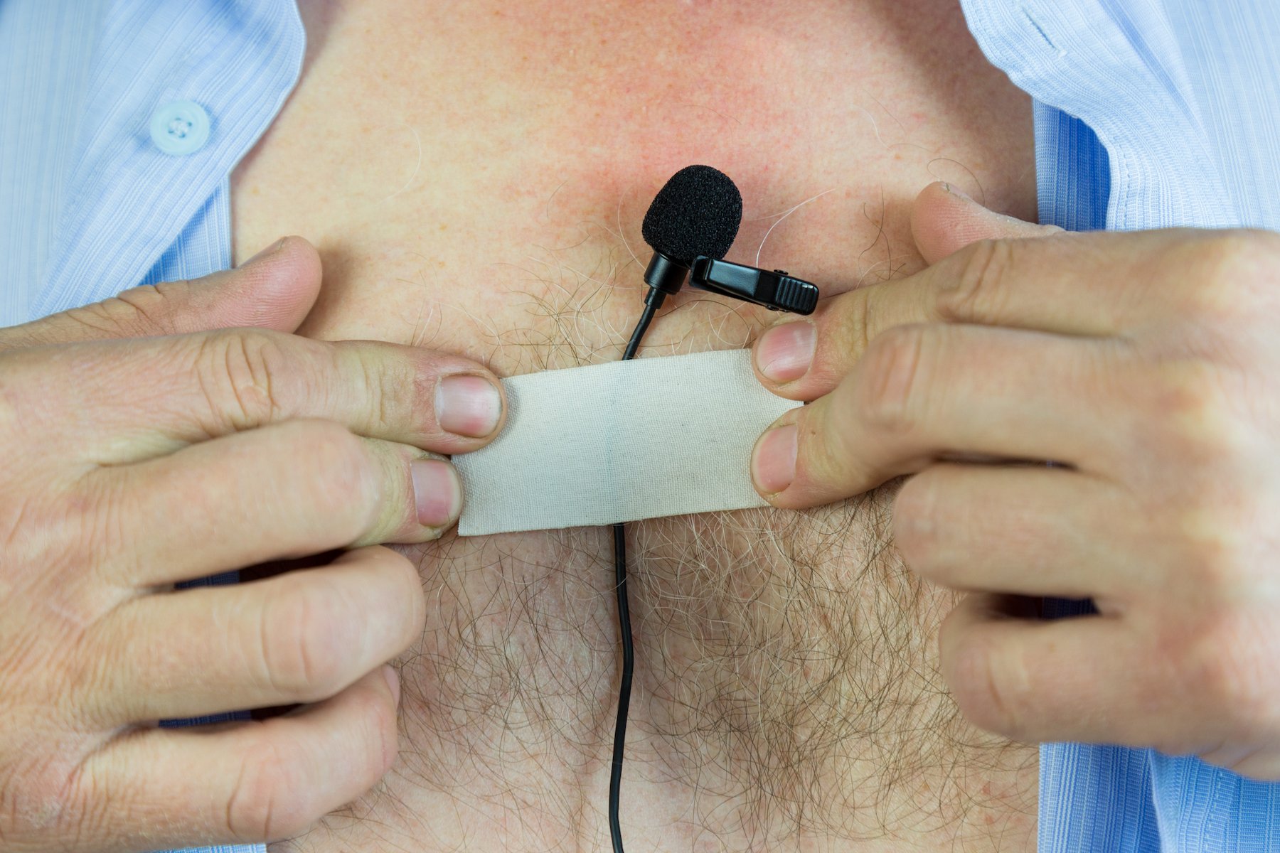 Man sticking a bug to his chest in order to record a conversation in violation of NRS 200.650.