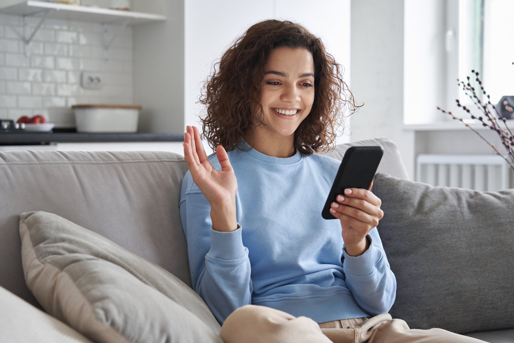 Woman speaking into a smartphone on her living room couch