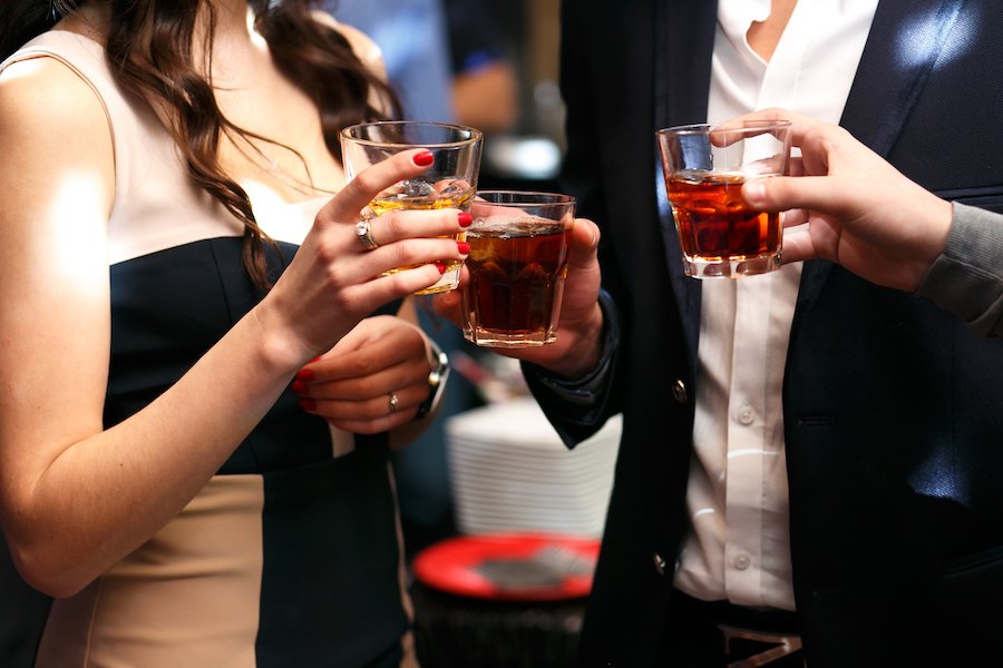 Close-up of a woman and a man holding alcohol at a party