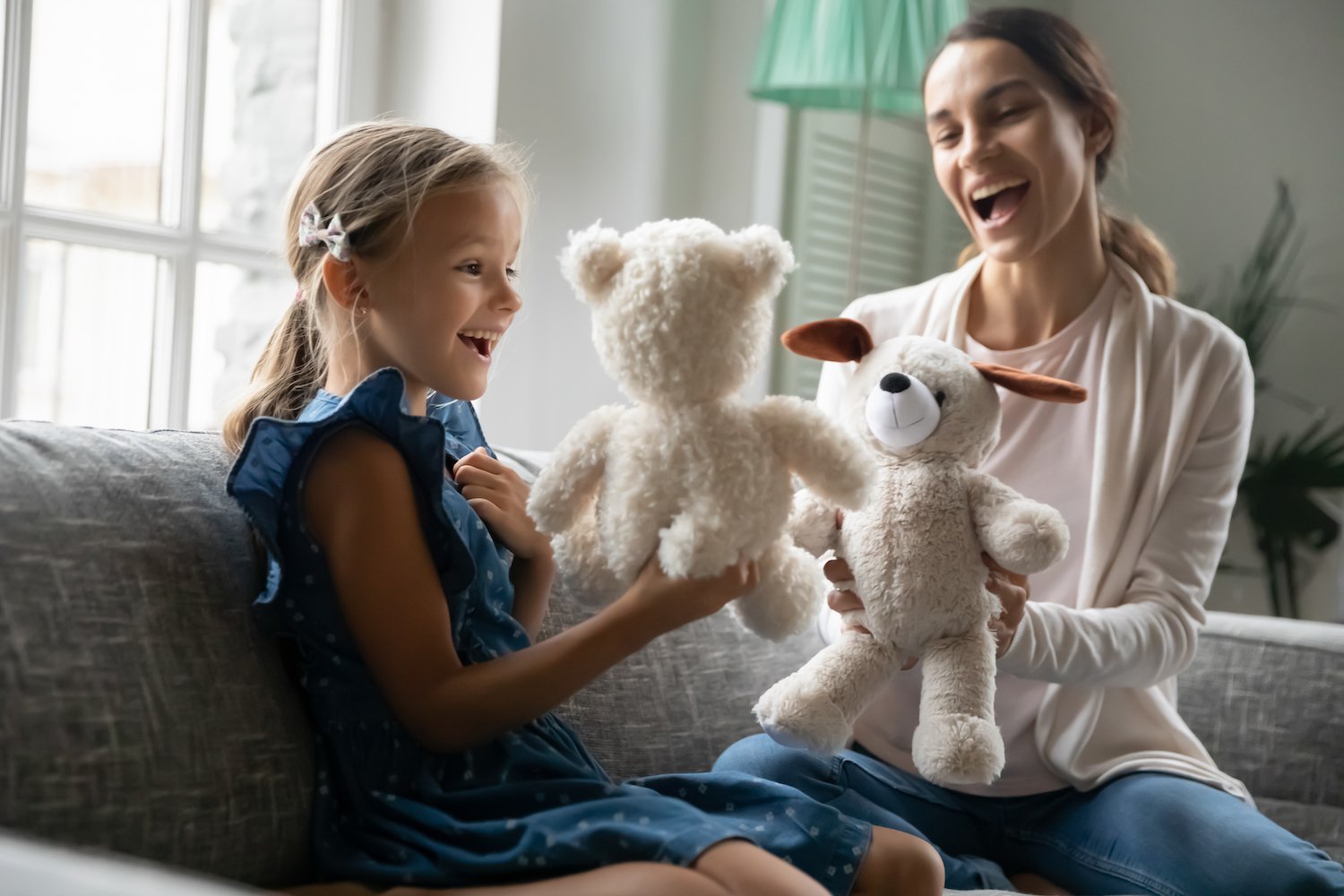 Teen babysitter with a young child playing with stuffed animals