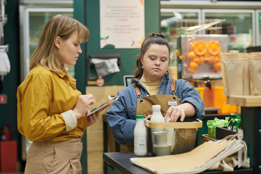 Woman with Downs Syndrome working with a supervisor in a store