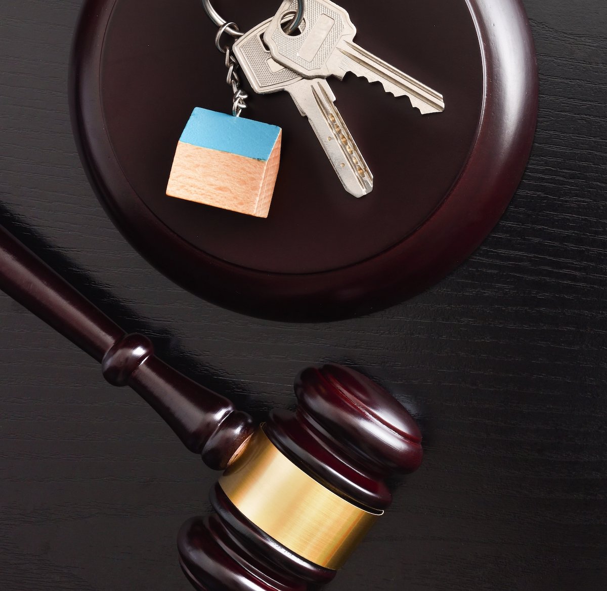 Overhead view of judge's gavel with house keys and a keychain with a house charm