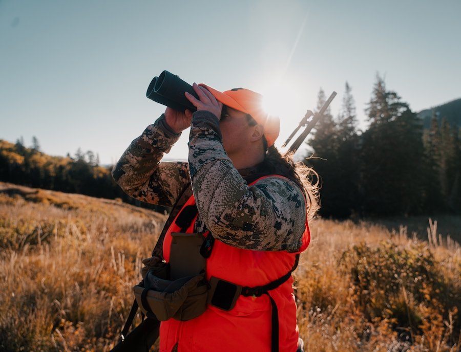 Hunter in orange vest looking through binoculars in northern Nevada wilderness