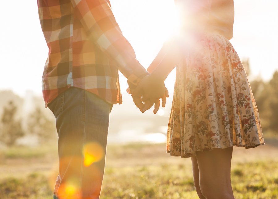 Man holding hands with a teenage girl while watching the sunset