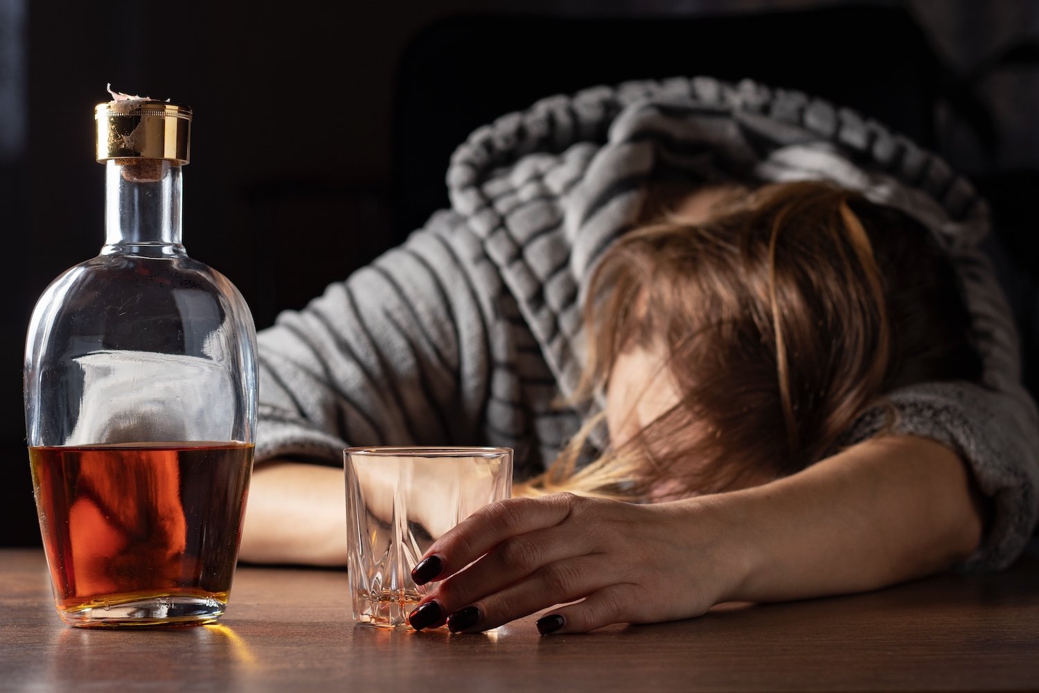 Mujer borracha desmayada en un bar junto a un vaso de alcohol