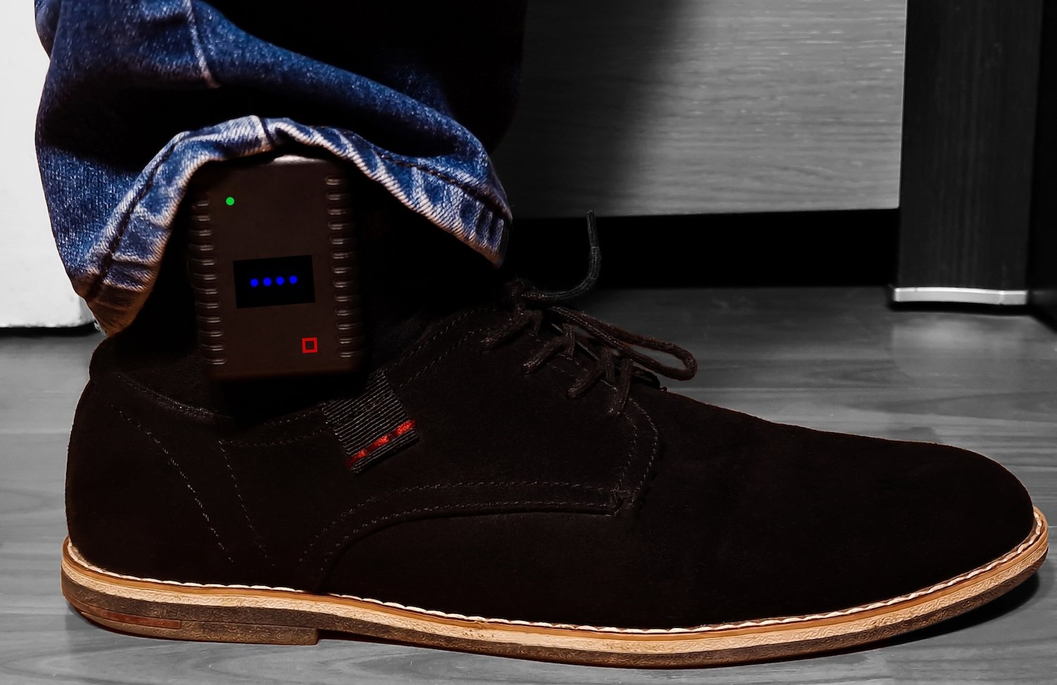 Close up of man's ankle monitor hidden by his jeans and sneaker