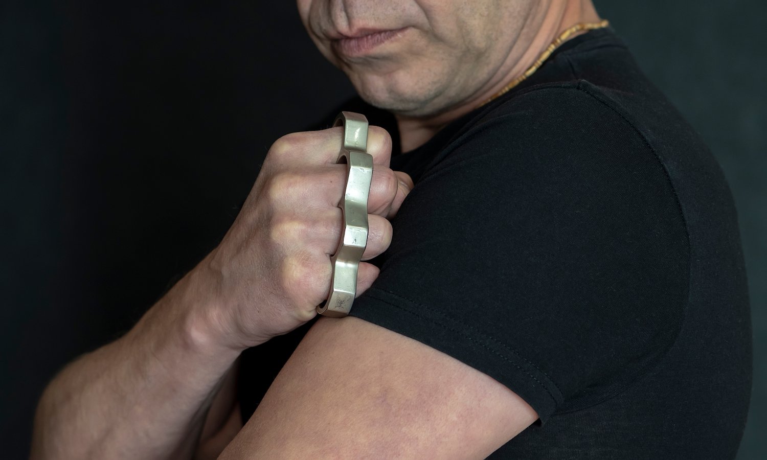 Man in black t-shirt holding up his fist with brass knuckles