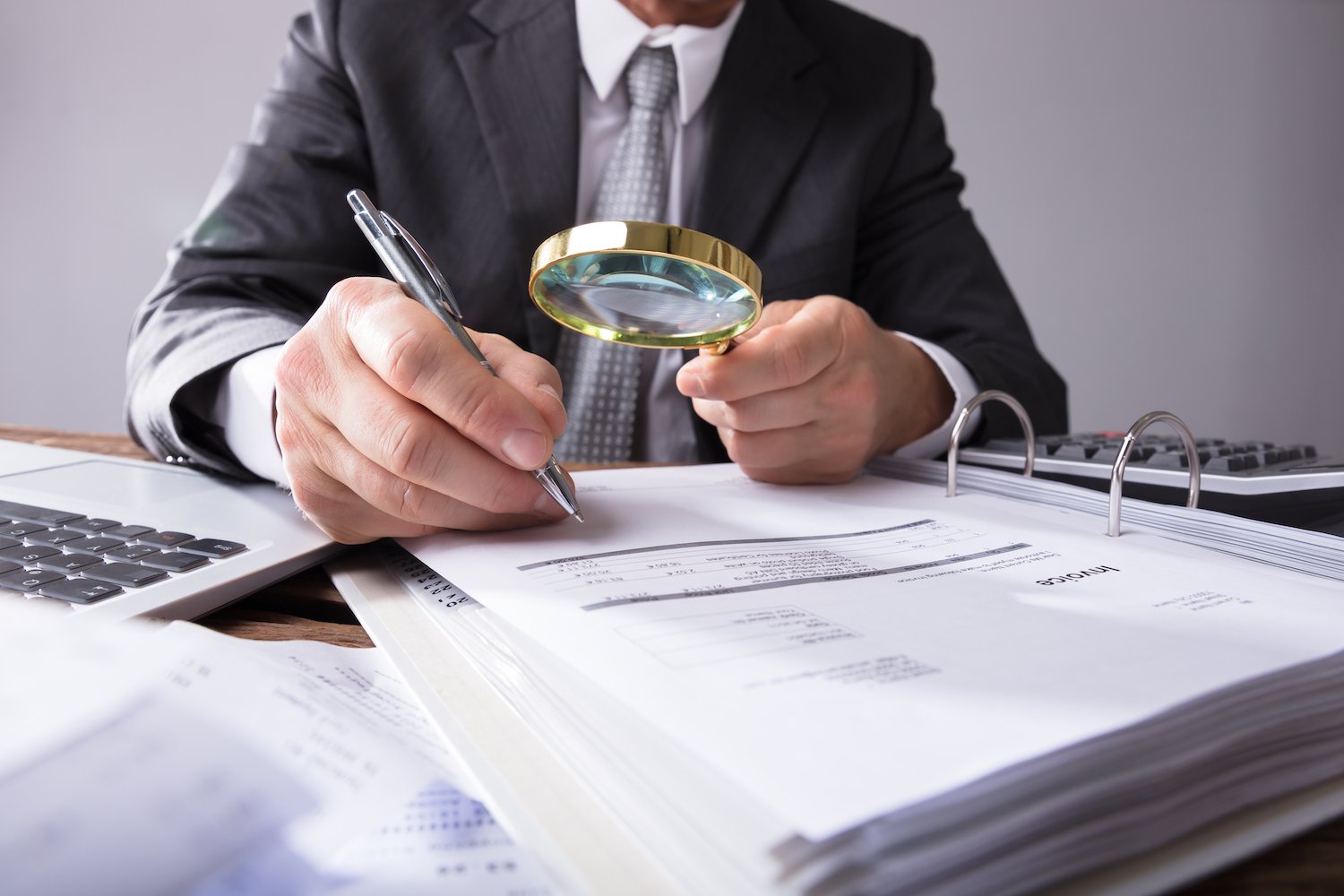 forensic analysis with a magnifying glass studying a check at his desk
