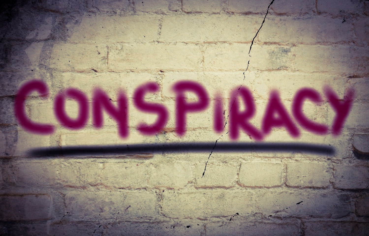 Brick wall that says "conspiracy" with red spray paint