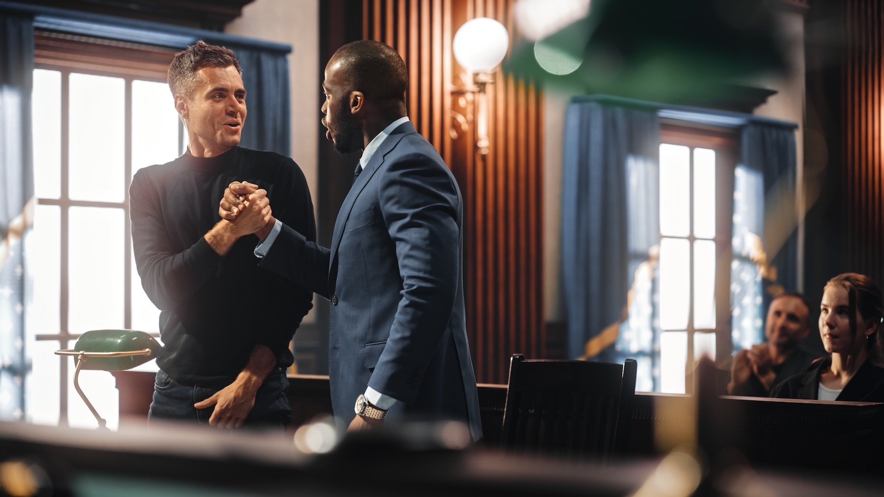 Criminal defense attorney and defendant shaking hands after a successful preliminary hearing in a courtroom