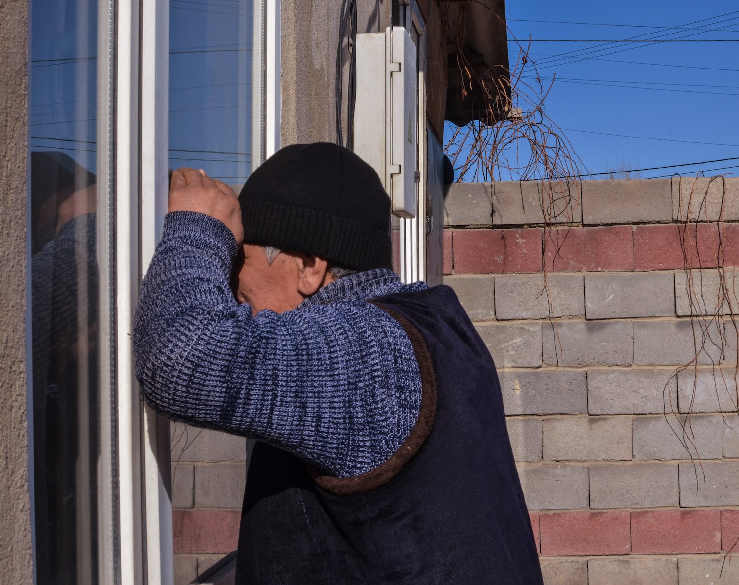 Hombre espiando dentro de una residencia privada a través de una puerta corrediza de patio de vidrio
