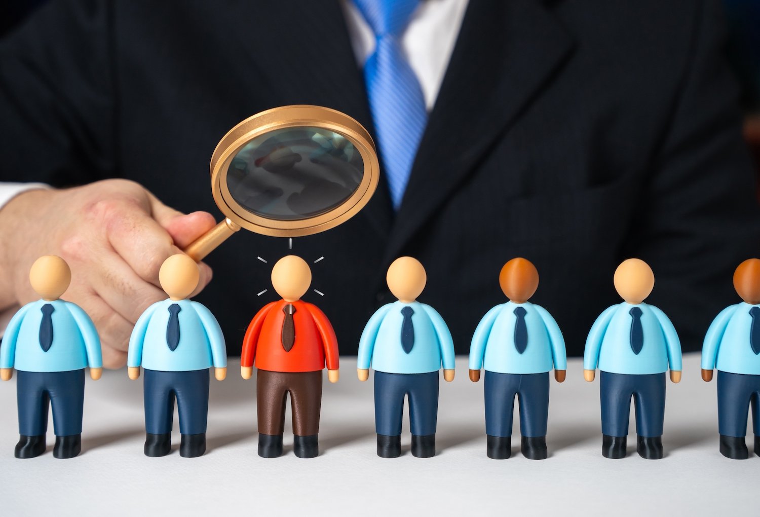 Lupa sobre muñecos de empleados para significar una investigación en el lugar de trabajo