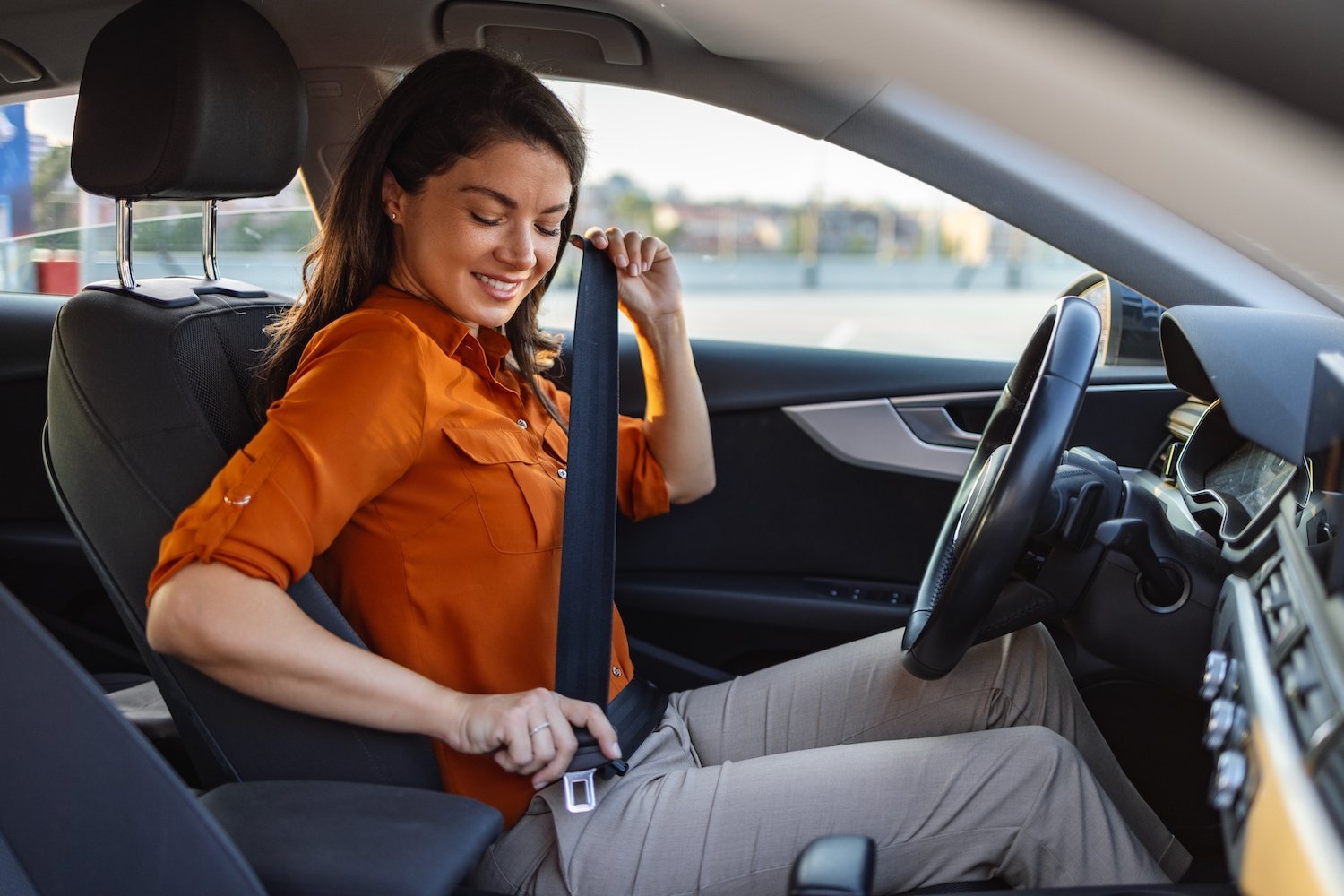 Female driver fastening herself into a car in a sedan