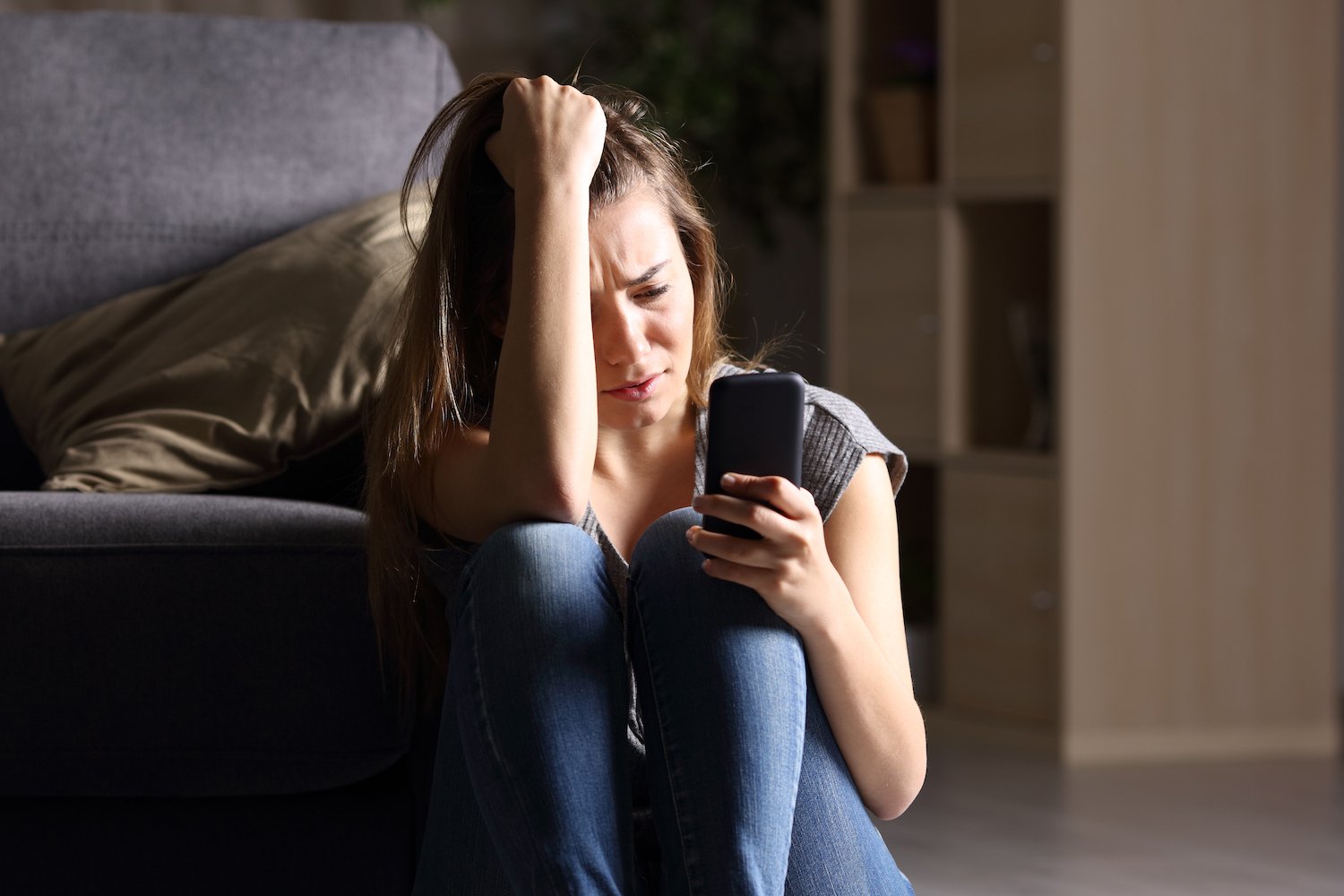 Anguished victim staring at her phone after receiving harassing text messages