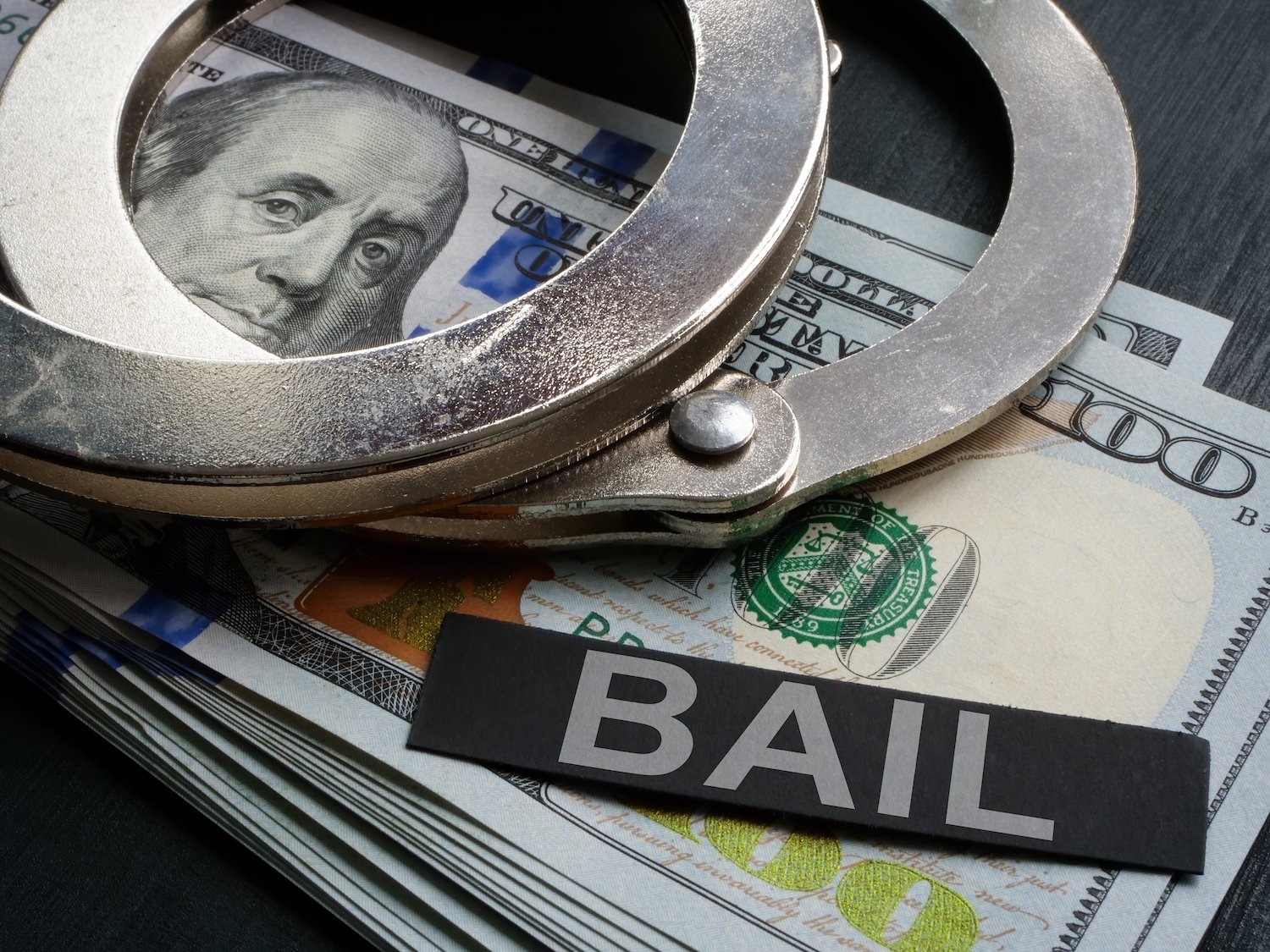 Wad of cash, handcuffs, and a sign that says "bail"