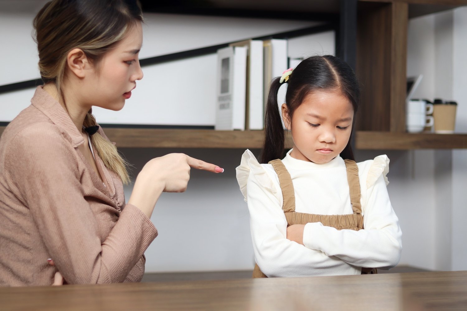 Mujer reprendiendo a una niña pequeña en un aula