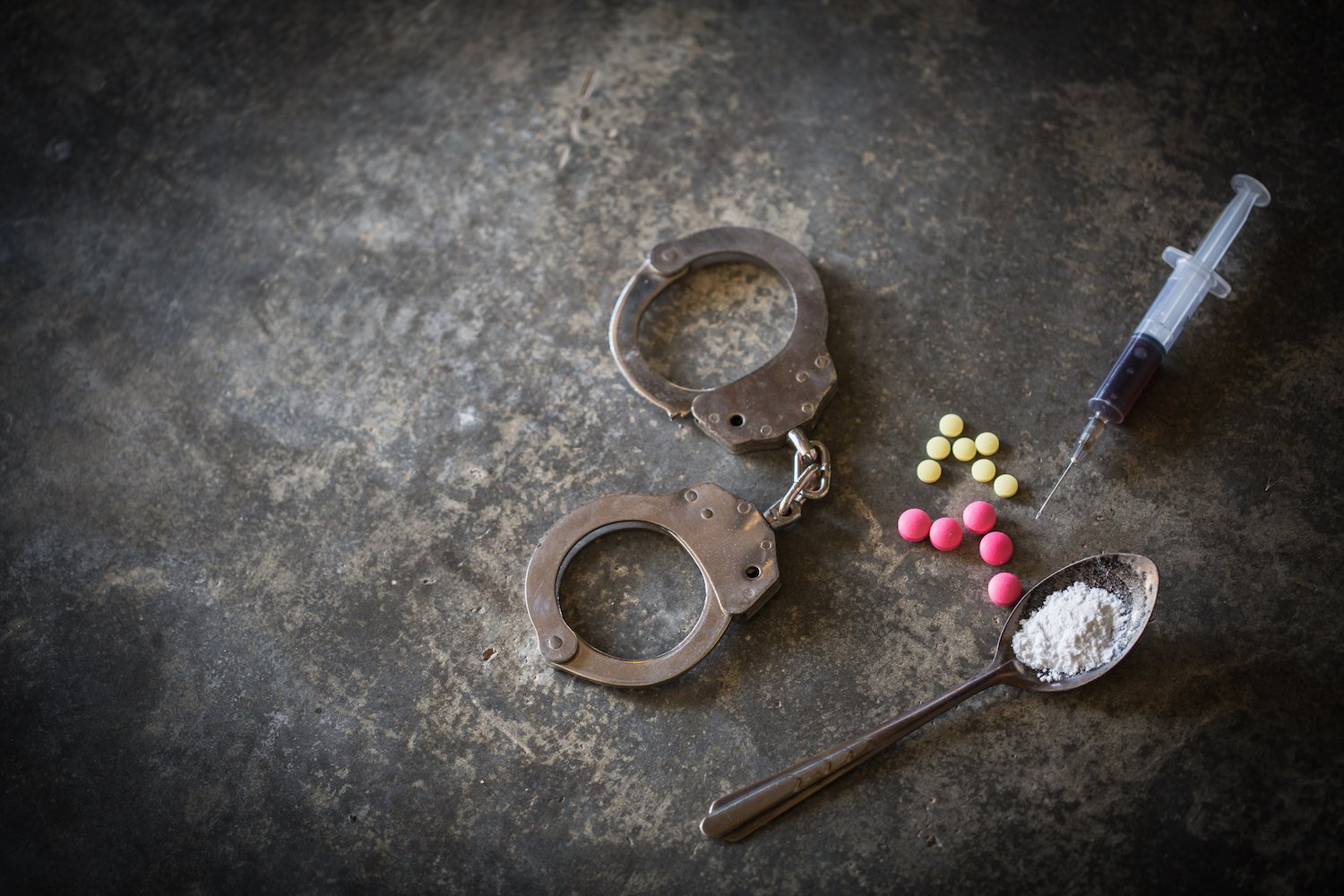 Esposas con drogas, heroína y una jeringa sobre una mesa