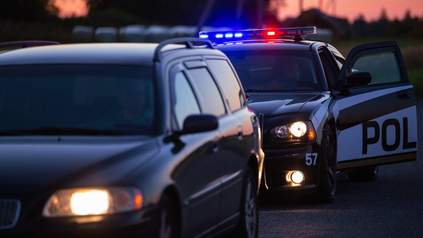 Auto policial deteniendo una SUV tras una infracción de tráfico al anochecer
