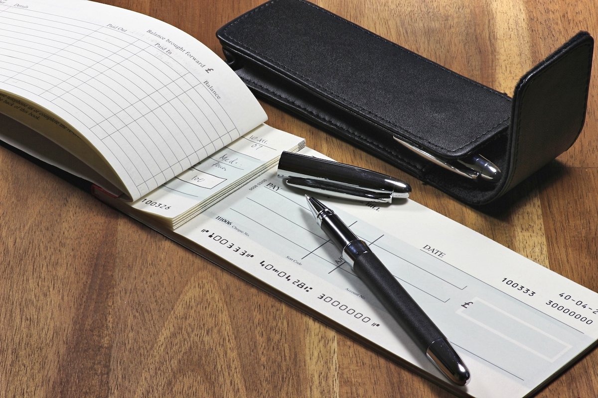 A checkbook with a pen on a wooden desk
