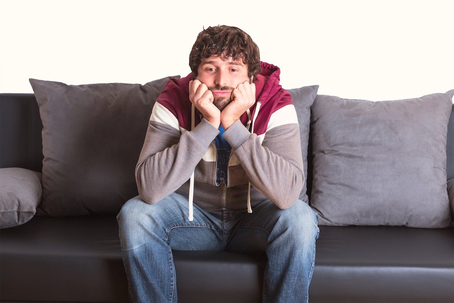 Hombre en arresto domiciliario sentado aburrido en el sofá