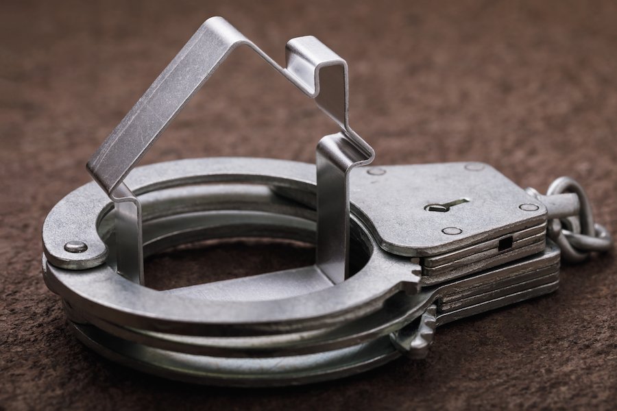 Primer plano de esposas con un cortador de galletas en forma de casa dentro de las esposas