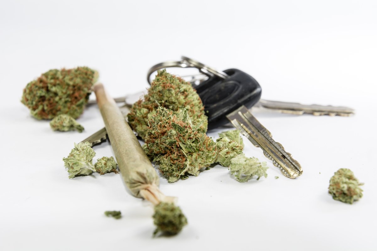 Car key next to marijuana and a joint on a white table