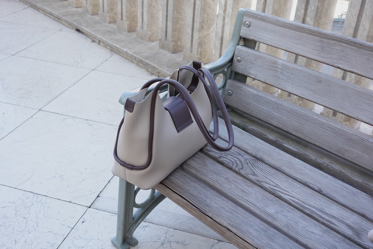 Woman's purse resting on park bench 