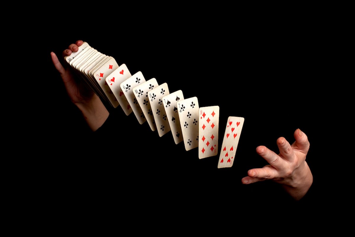 Magician's hands shuffling a deck of cards against a black background