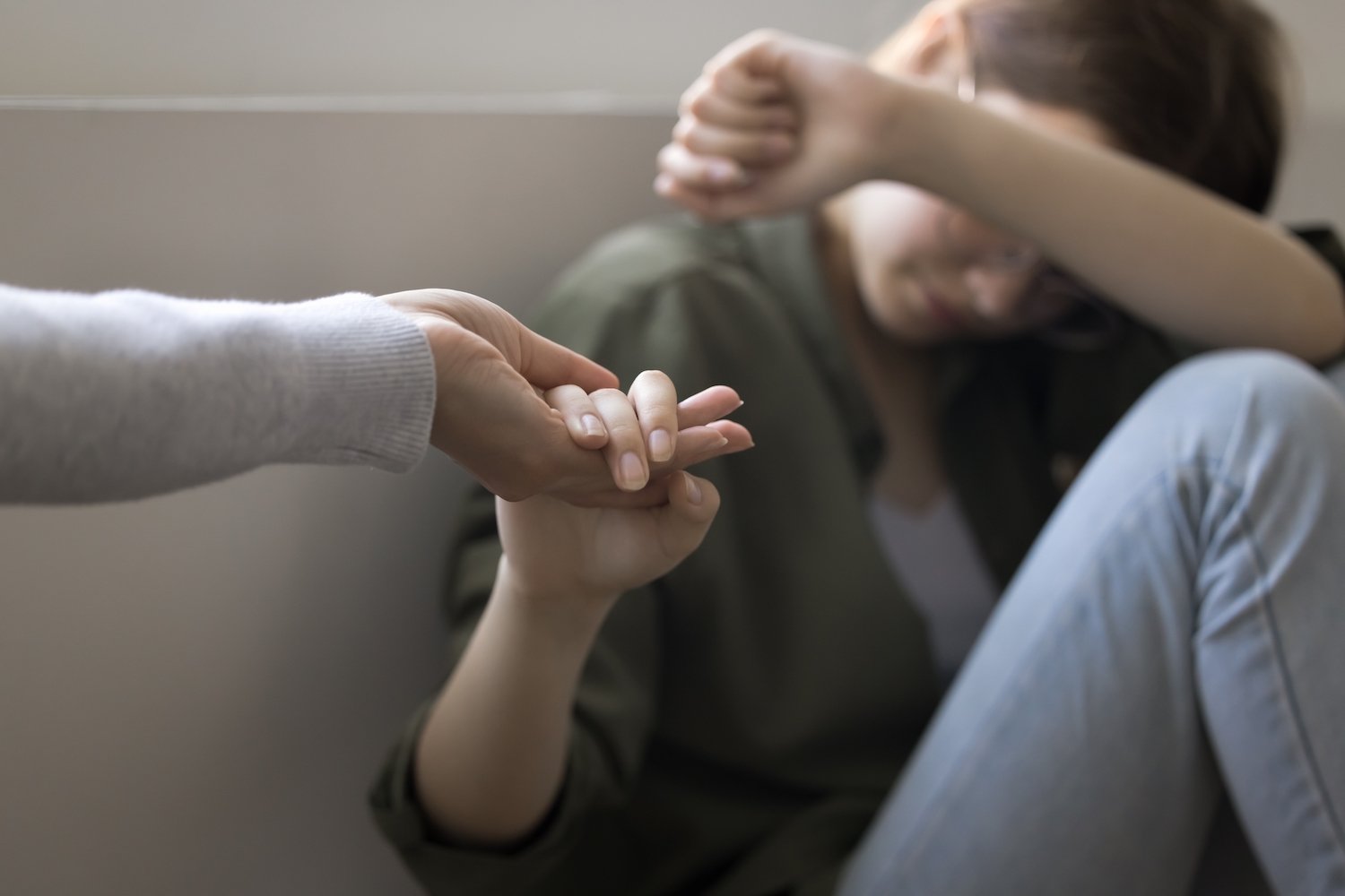 Adolescente con problemas tomando la mano de un adulto que se la extiende