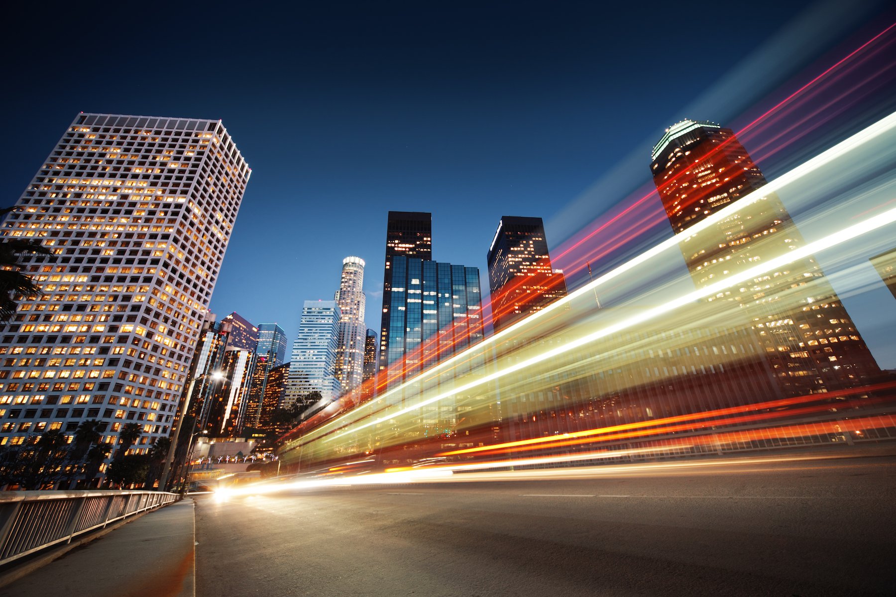 Los Angeles at night with a long exposure shot of blurred car speeding through night street.