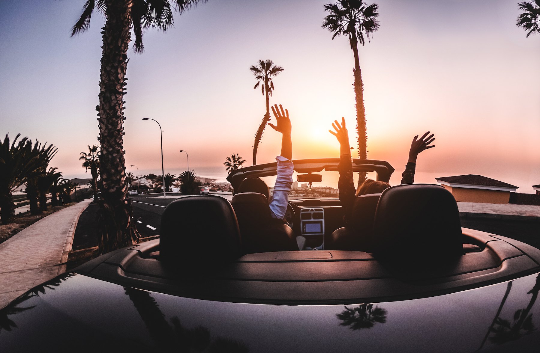 Joy riders in a convertible on a Los Angeles road at sunset