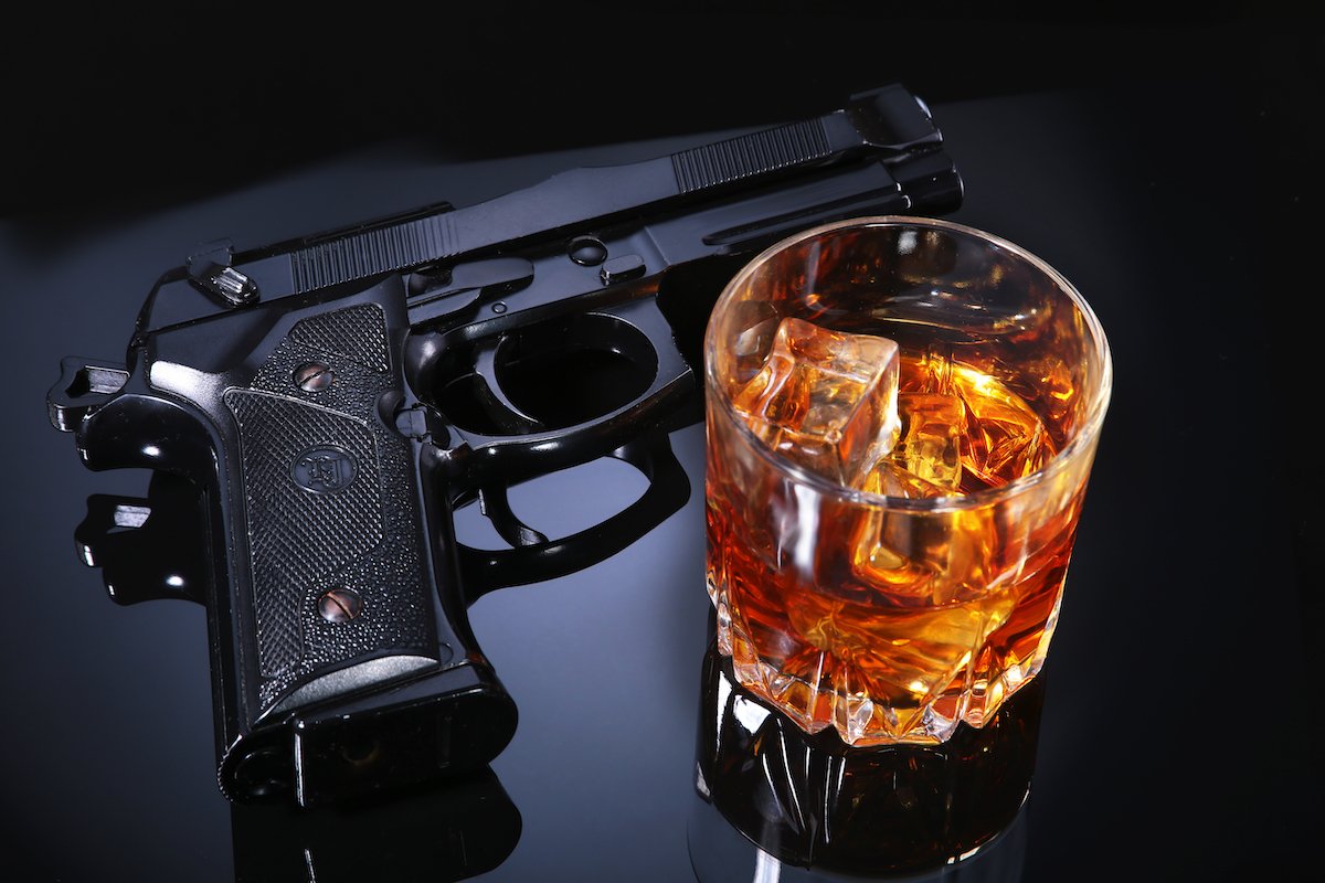 Revolver and a tumbler of alcohol on a black table