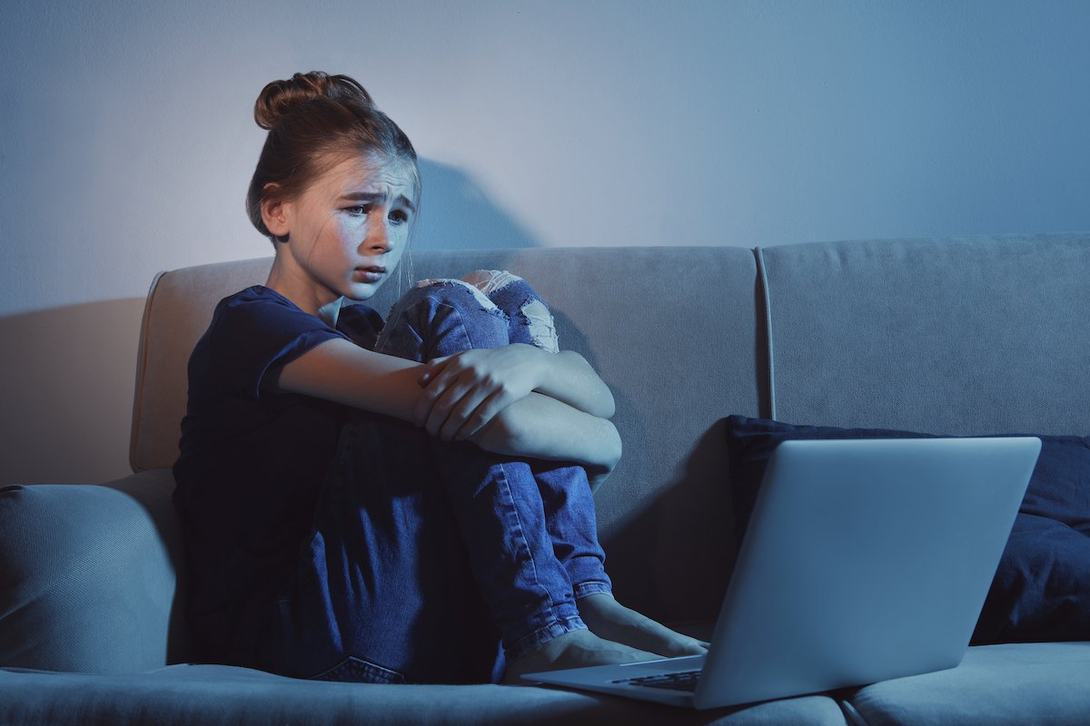Distressed young girl on a couch in front of her laptop