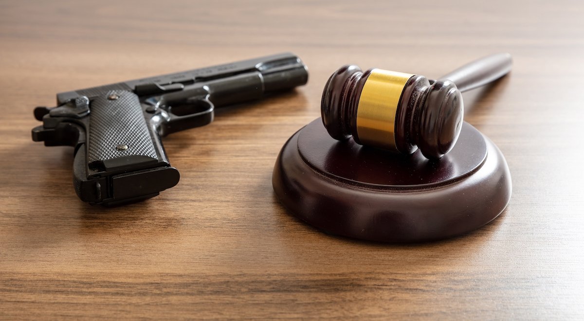 Gavel next to a gun on a wooden table