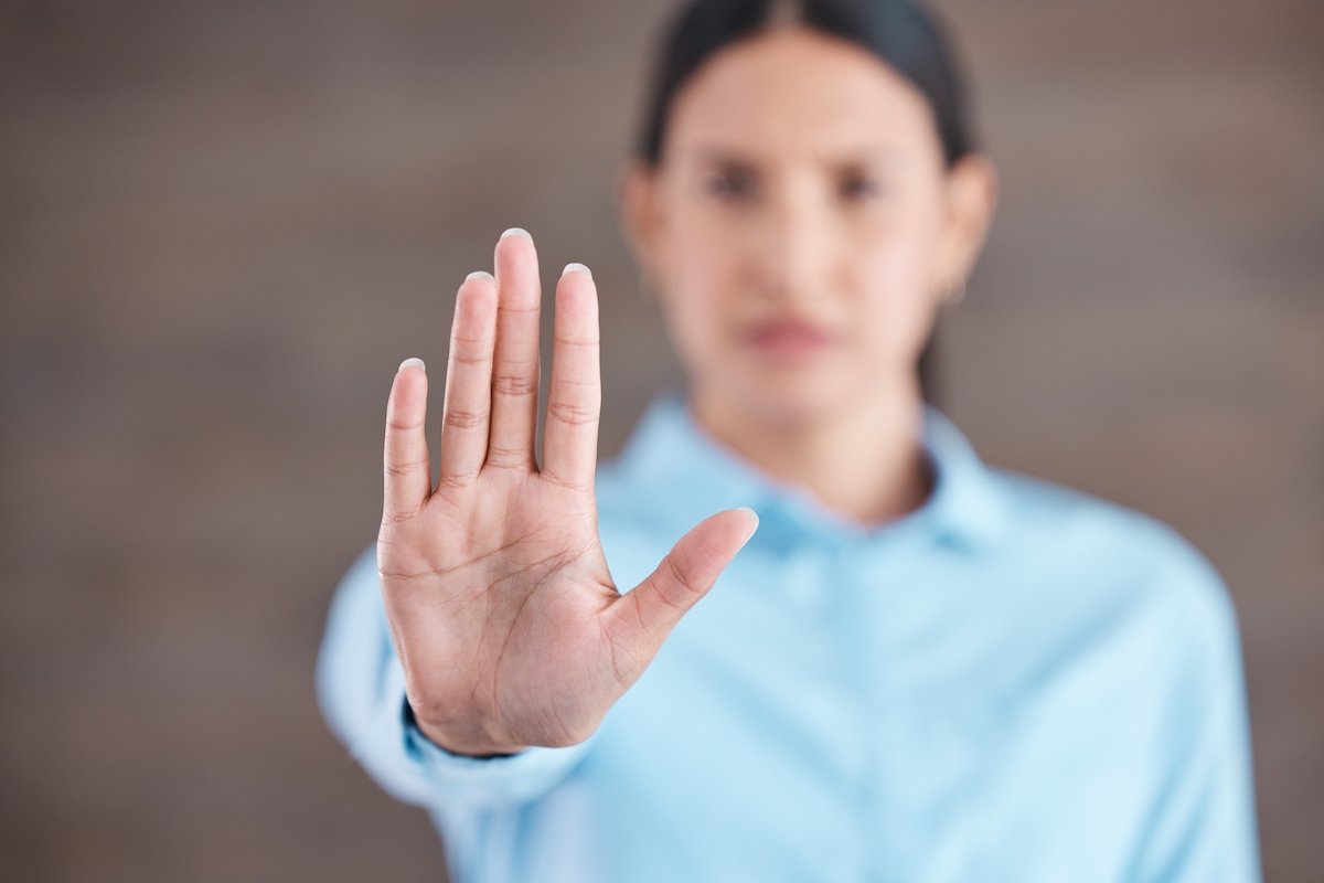 Female office worker holds out her hand to stop a co-worker from approaching.