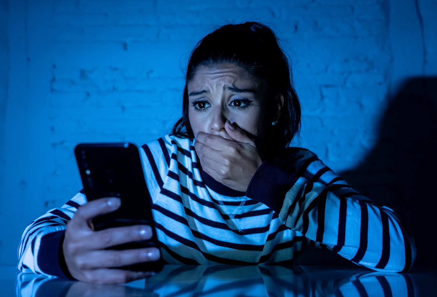 Víctima de acoso luciendo angustiada después de mirar su teléfono