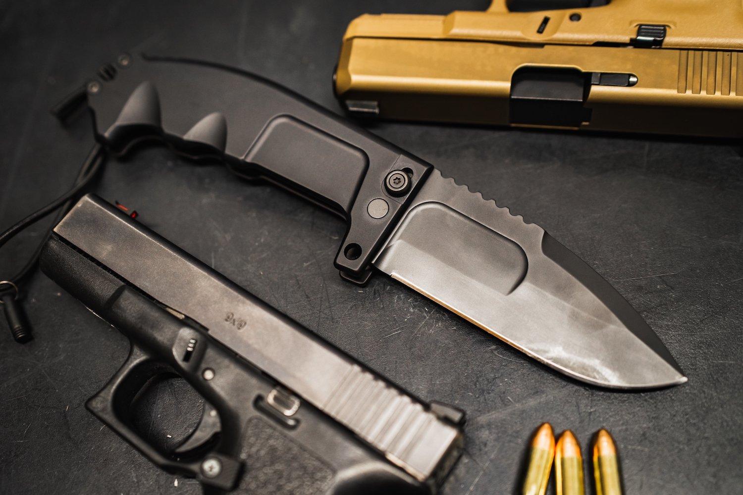 Pistola, cuchillo y municiones sobre una mesa negra, que son armas que pueden usarse para robo agravado