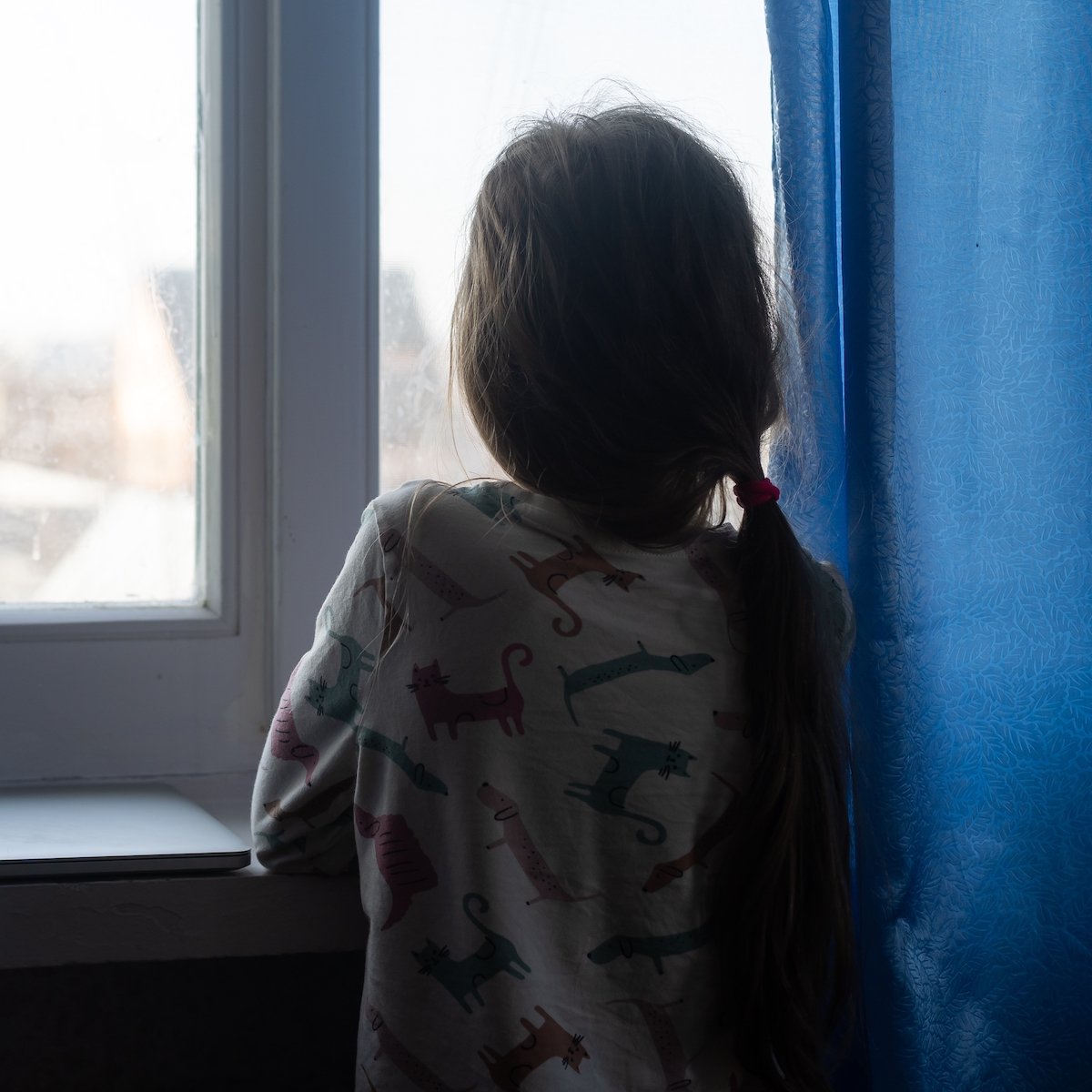 Neglected young girl looking forlorn out the window