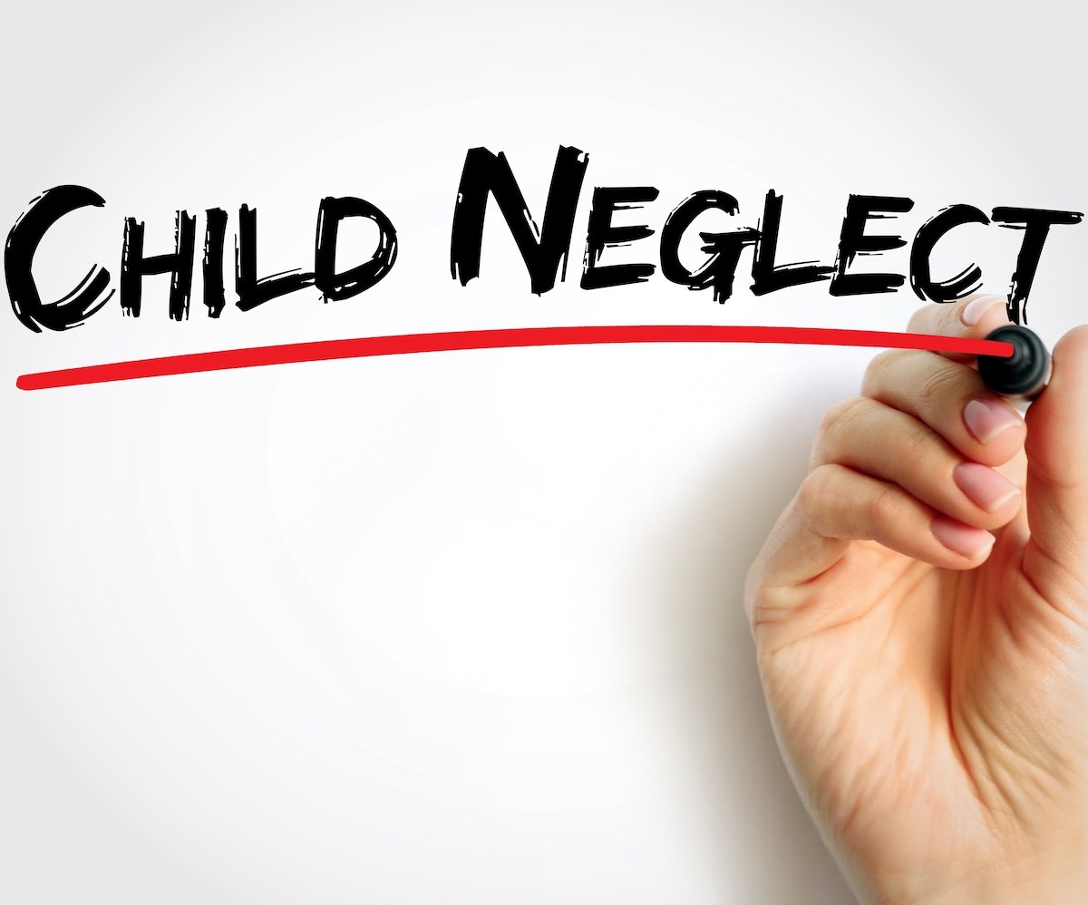 Hand writing "child neglect" on a white board in black marker with a red underline
