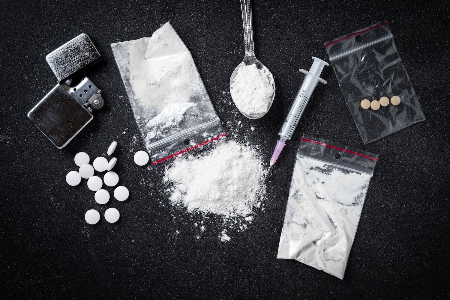 Cocaine, heroin, and pills on a black table
