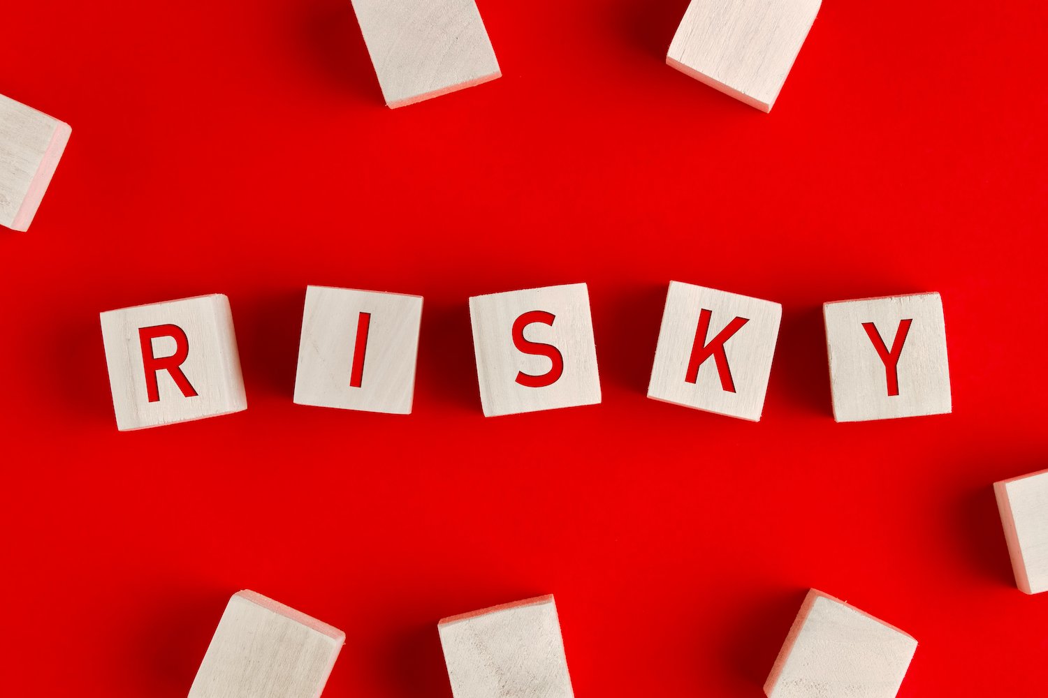 Fichas de Scrabble que forman la palabra "Risky" sobre una mesa roja