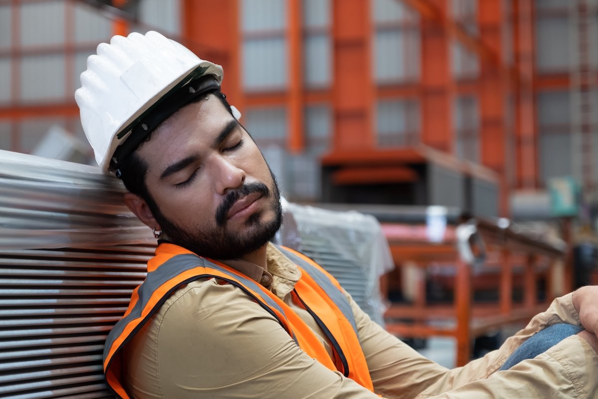 Trabajador de almacén tomando una siesta con su casco de seguridad