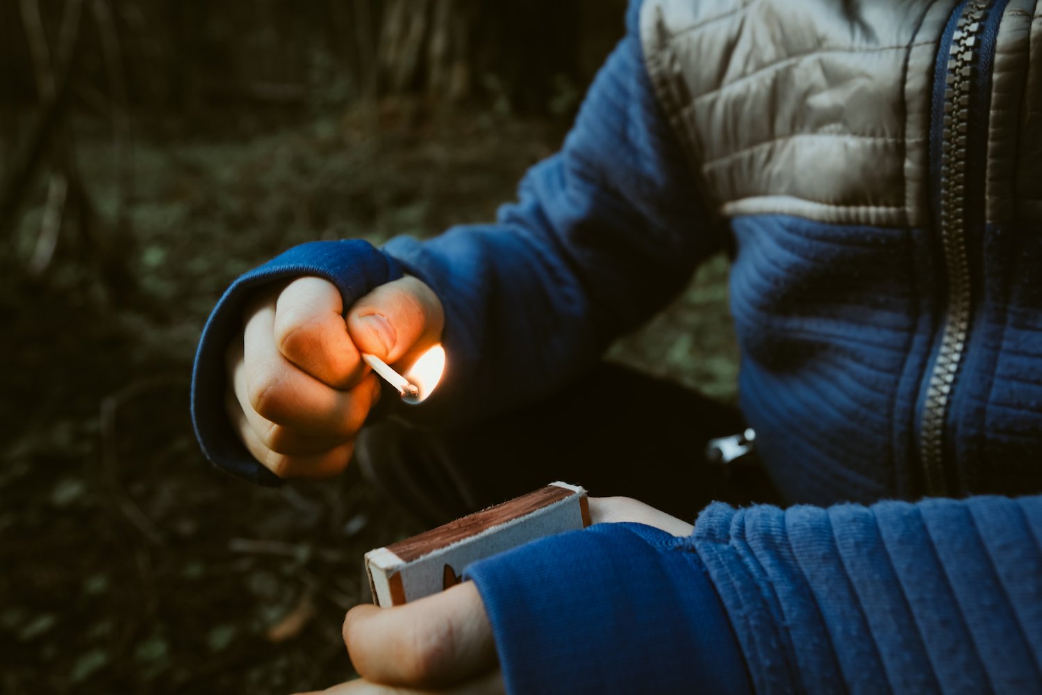 Person lighting a match in a wooden area in an act of arson