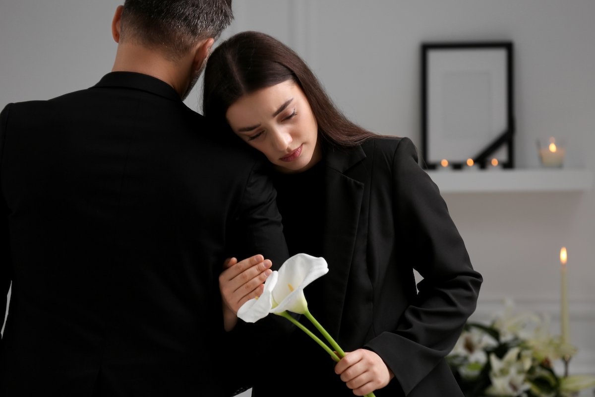 Sad couple with calla lily flowers mourning indoors at a funeral home