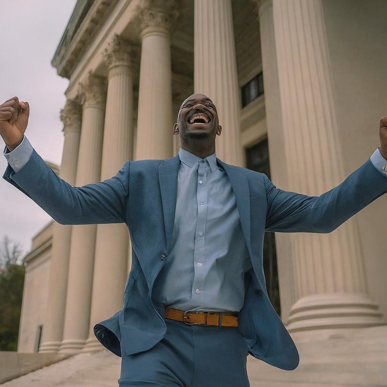 Hombre levantando los puños triunfante frente a un tribunal tras una moción post-condena exitosa