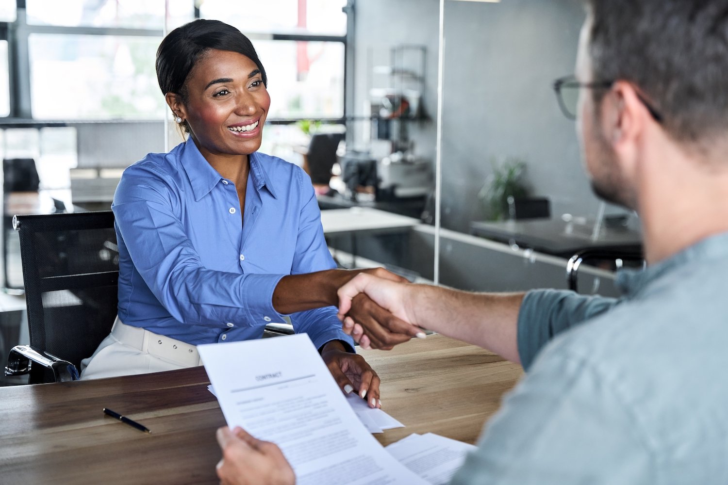 Solicitante de empleo sonriente estrechando la mano de su entrevistador